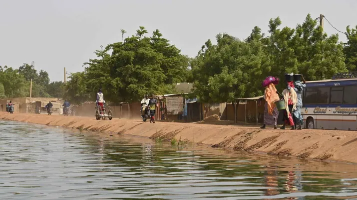 Des populations marchent le long d'un cours d'eau.