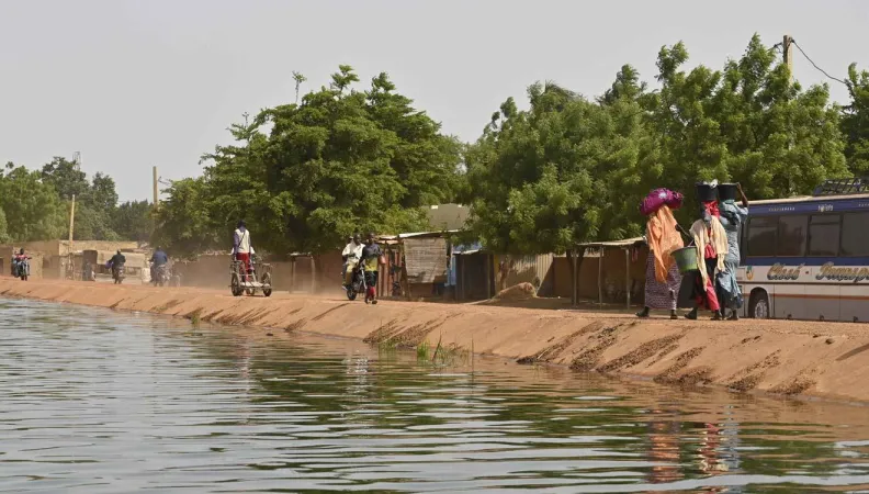 Des populations marchent le long d'un cours d'eau.